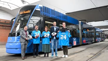 Mehrere Personen mit Carolina Panthers Trikots stehen vor einer Tram Bahn