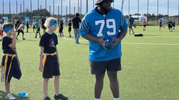 Der NFL-Spieler Ickey Ekwonu mit Kindern bei einem Flag Football Camp in München