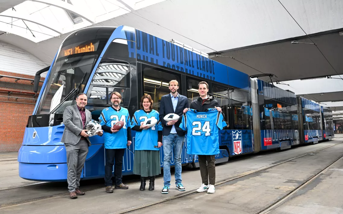 Mehrere Personen mit Carolina Panthers Trikots stehen vor einer Tram Bahn