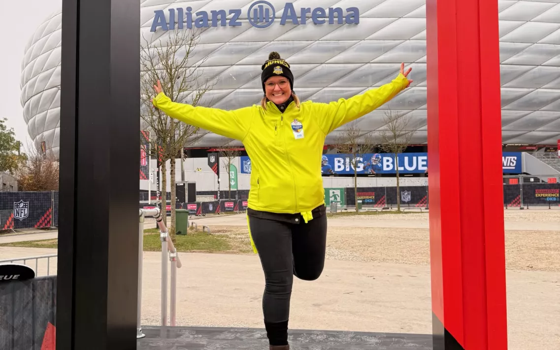 Eine Frau steht in einem überdimensionalen Bilderrahmen, vor der Allianz Arena in München