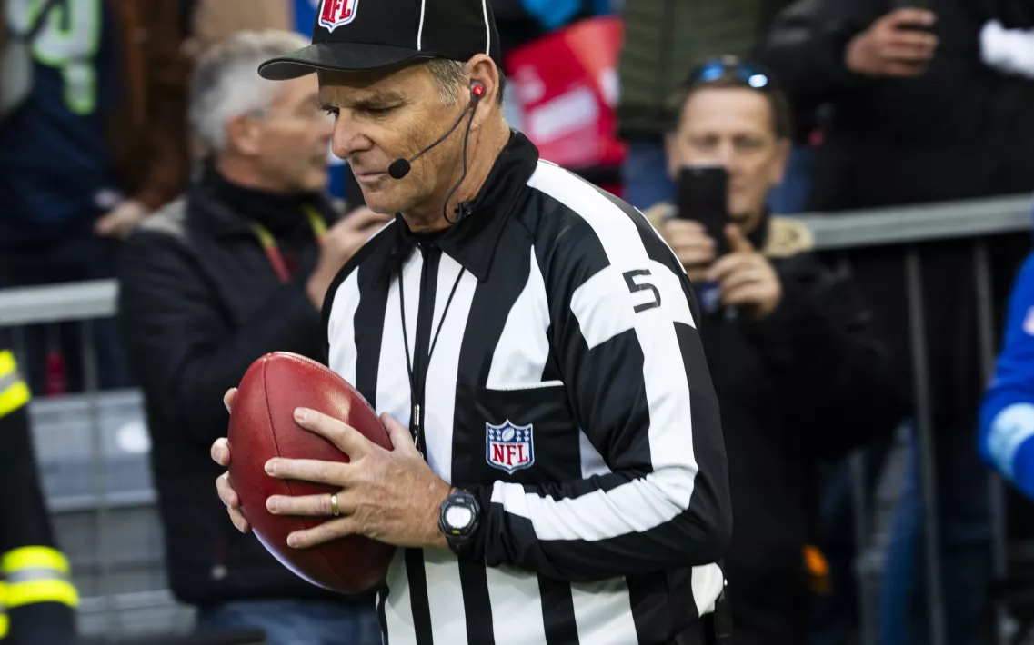 Ein NFL-Schiedsrichter mit einem Ball in der Hand während des Munich Game 2024